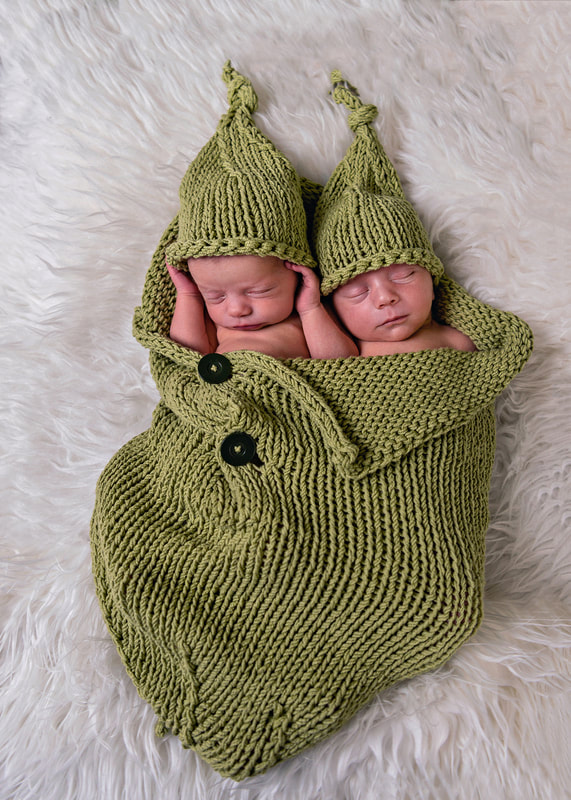photo of a newborn baby girl and boy laying together in a knit pea pod with green hats 