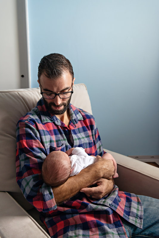 photo of a man who is a new father holding and looking down on his newborn baby boy