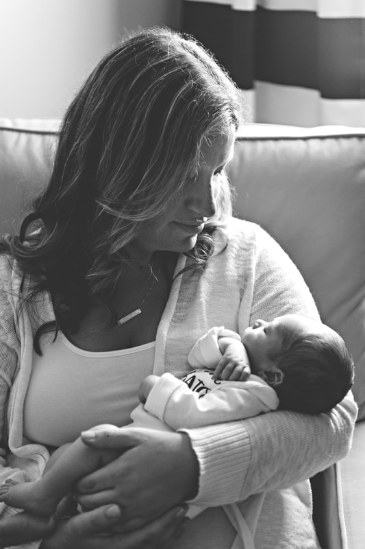 black and white photo of a woman who is a new mother looking down at her newborn baby boy 